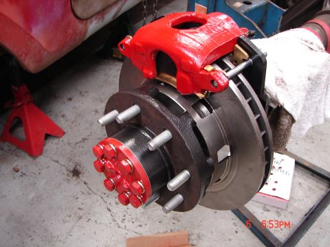 1989 Ford Bronco - Close-up of a vehicle's brake assembly, showing a red caliper and a vented rotor.