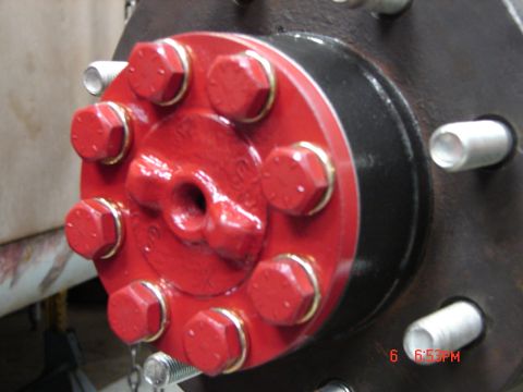 1989 Ford Bronco - Close-up view of a red axle hub assembly with eight bolts and gold washers visible.