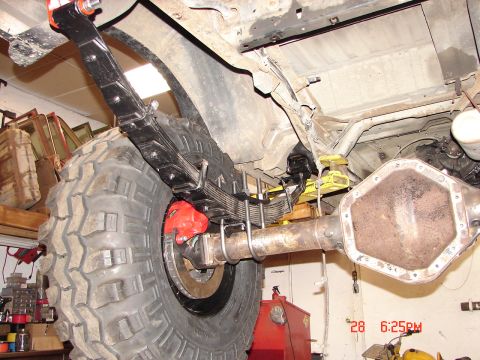 1989 Ford Bronco - Underside view of a vehicle's rear axle and suspension system, showing large tires and brake components.