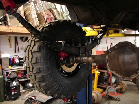 1989 Ford Bronco - Close-up view of a vehicle's rear axle and suspension system, showing a large off-road tire and leaf springs.