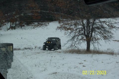 1978 Ford Bronco - A Jeep Wrangler navigates a snow-covered landscape, with a solitary tree in the background.