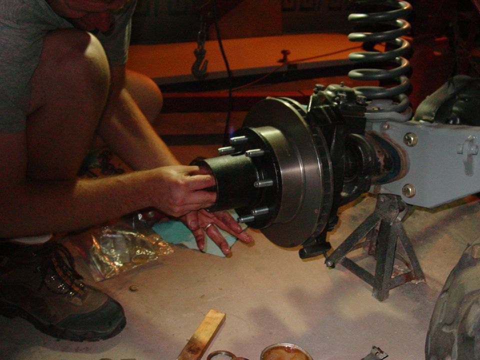 Front axle assembly on jack stands, being worked on by a person