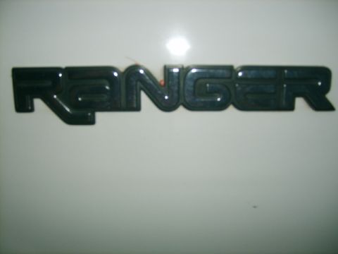 1993 Ford Bronco - A close-up of a black Ranger emblem is visible on a white background.