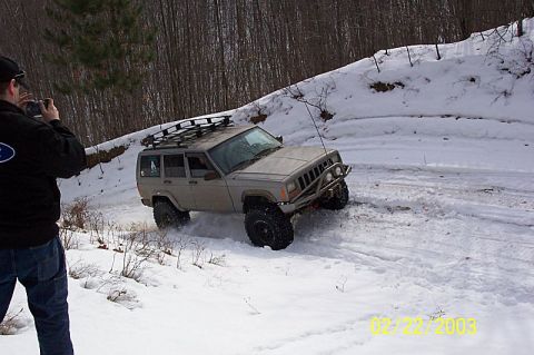 1978 Ford Bronco - A Jeep Cherokee XJ navigates a snowy trail with a photographer capturing the action.