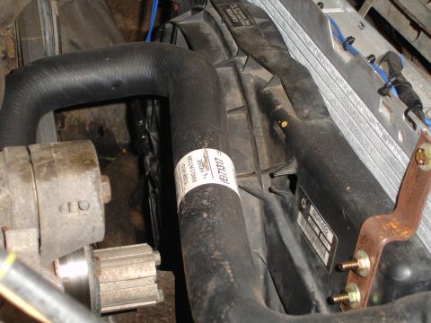 1989 Ford Bronco - Close-up of a radiator fan shroud and hoses, with a part number visible on a label.