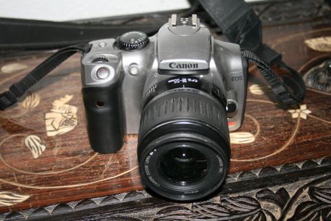 2003 Jeep TJ - A silver Canon EOS camera with a black lens and strap rests on a carved wooden surface.