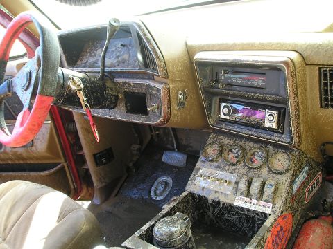 1989 Ford Bronco - The interior of a vehicle is heavily covered in mud, suggesting recent off-road use.