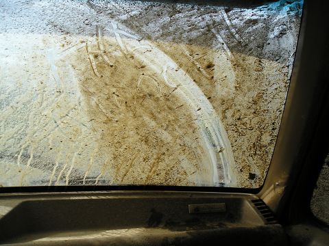1989 Ford Bronco - The interior view shows a heavily soiled windshield with visible wiper marks and mud splatter.