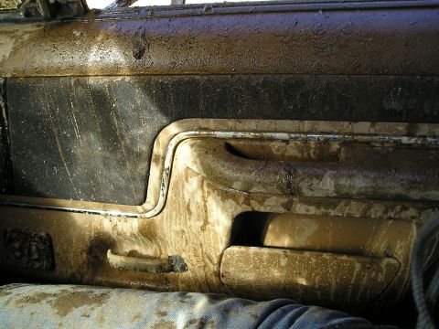 1989 Ford Bronco - The interior door panel of a vehicle is heavily covered in mud, obscuring most details.