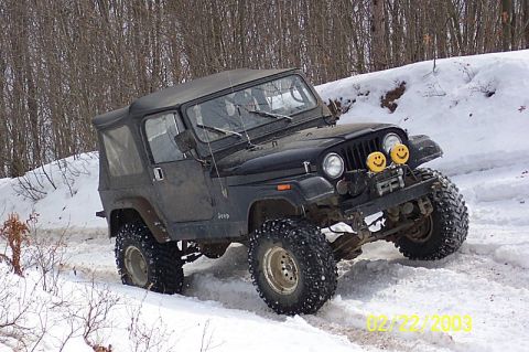 1978 Ford Bronco - Black Jeep Wrangler navigates snowy terrain with aggressive tires and a soft top.