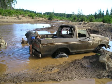 1989 Ford Bronco - A person attempts to free a muddy 1978 Ford Bronco from a deep mud pit.