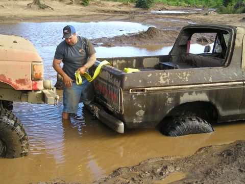 1989 Ford Bronco - A man attempts to tow a mud-covered 1978 Ford Bronco out of a muddy water hole.