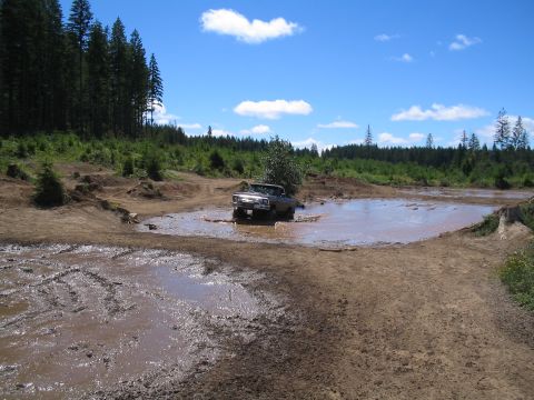 1989 Ford Bronco - Truck navigating a muddy obstacle course on a sunny day.