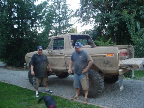 1989 Ford Bronco - Two men stand beside a heavily muddied 1979 Ford F-Series pickup truck, likely after off-road use.