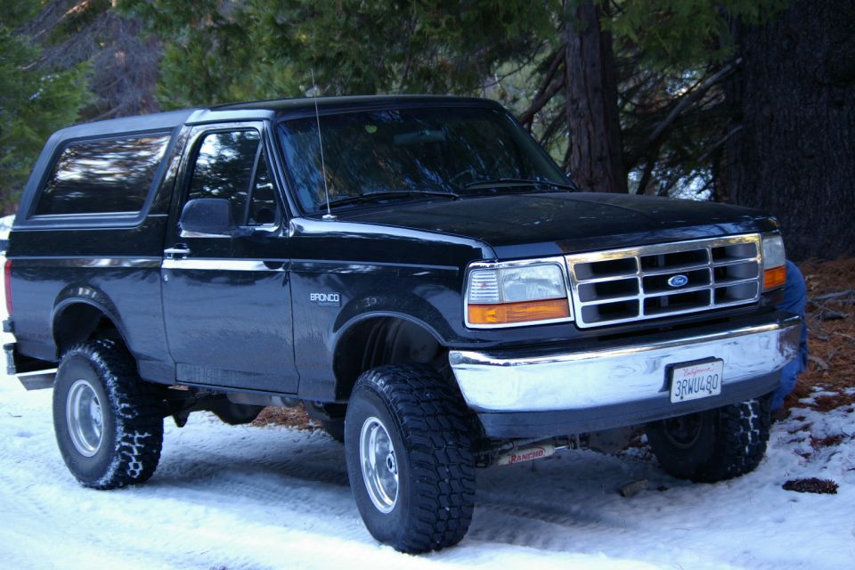 Black 1996 Ford Bronco with lifted suspension parked in snow