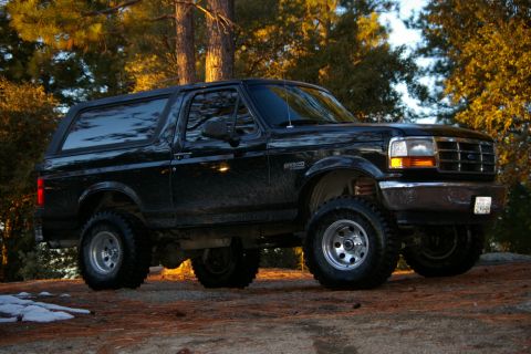 1996 Ford Bronco - This black 1996 Ford Bronco is shown in a three-quarter front view, parked in a natural setting.