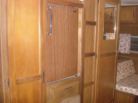 1994 Ford Bronco - The interior of a camper shows wood paneling, cabinets, and a couch with a floral pattern.