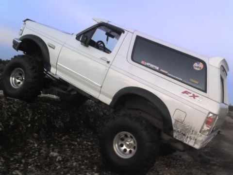 1995 Ford Bronco - White 1995 Ford Bronco climbing over rocks, showing FX4 badging and aftermarket wheels.