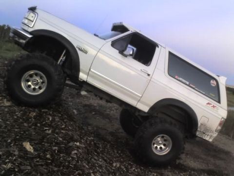 1995 Ford Bronco - White 1995 Ford Bronco modified for off-roading is shown climbing a dirt hill.