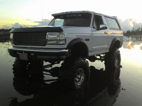 1995 Ford Bronco - A lifted 1995 Ford Bronco is parked in shallow water during sunset.