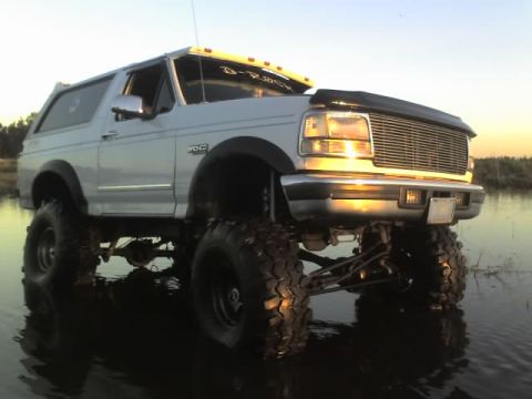 1995 Ford Bronco - This lifted 1995 Ford Bronco is shown off-roading in shallow water during a sunset.