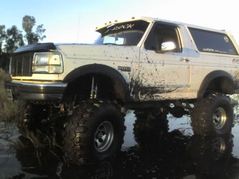 1995 Ford Bronco - This lifted 1995 Ford Bronco is caked in mud after an off-road adventure, reflecting in the shallow water.