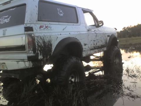 1995 Ford Bronco - This white 1992 Ford Bronco is stuck deep in the mud, with its tires submerged.