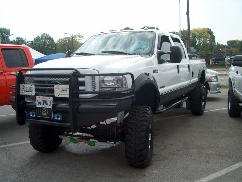 1978 Ford Bronco - A lifted white Ford F-Series truck is parked outdoors with other vehicles.