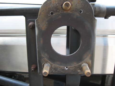 1994 Ford Bronco - Close-up of a surface-rusted steel spare tire carrier mounting plate welded to black tubing, with a large center hole, two protruding threa…