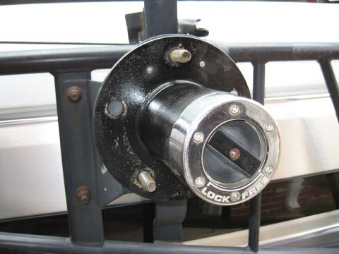 1994 Ford Bronco - Close-up of a black-painted front hub with a chrome manual locking hub cap marked "LOCK" and "FREE" and a slotted selector dial, wheel stud…