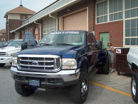 1978 Ford Bronco - A blue Ford F-350 Super Duty truck is parked in front of a brick building with large windows.