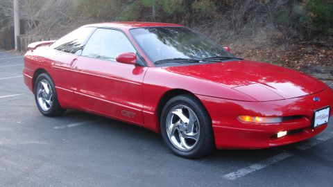 1996 Ford Probe - A red Ford Probe GT is parked in a lot with trees in the background.