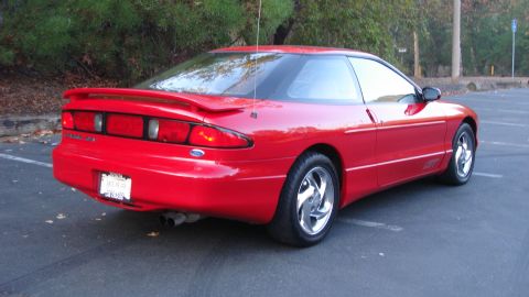 1996 Ford Probe - This red 1996 Ford Probe is shown from the rear 3/4 angle, a prominent spoiler and chrome wheels.