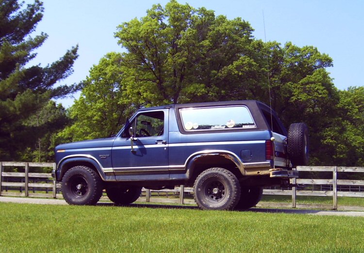 Blue and tan lifted two-door SUV with rear tire carrier on grass