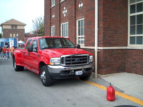 1978 Ford Bronco - A red Ford F-350 Super Duty pickup truck is parked on the street next to a brick building.