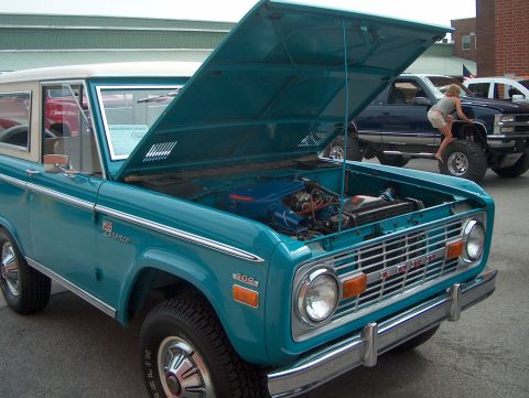 1978 Ford Bronco - Turquoise 1978 Ford Bronco on display with hood open, revealing the engine bay.
