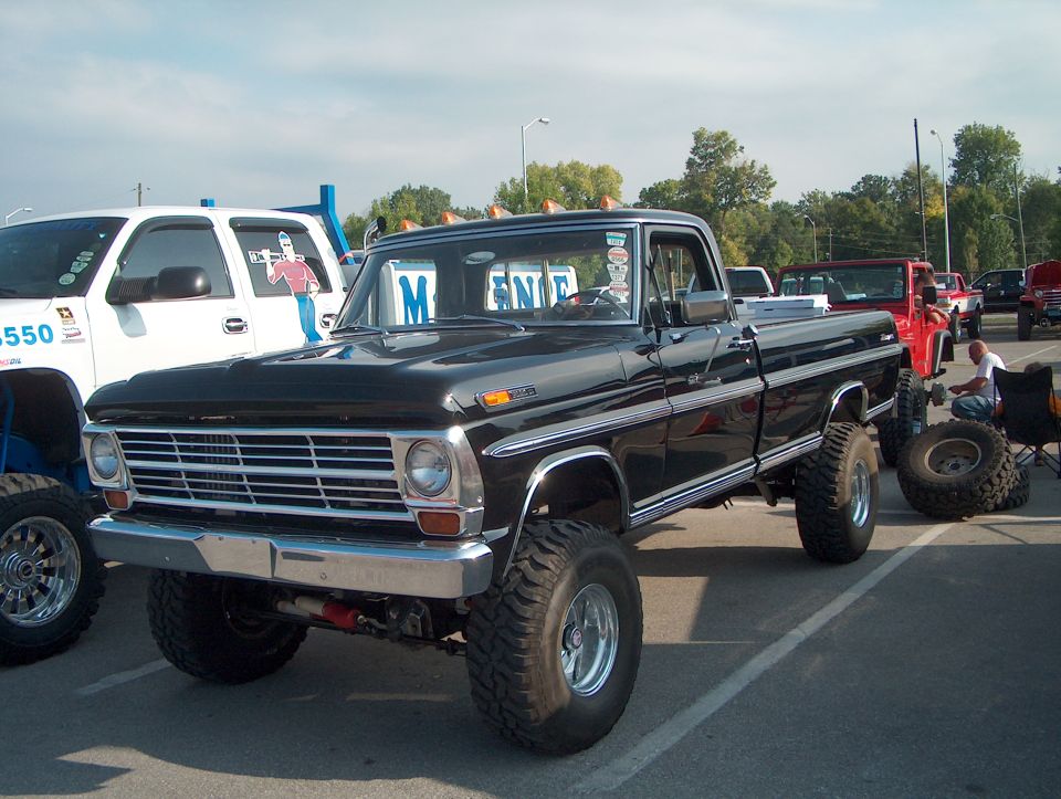 black lifted pickup truck with chrome trim, parked next to a white truck