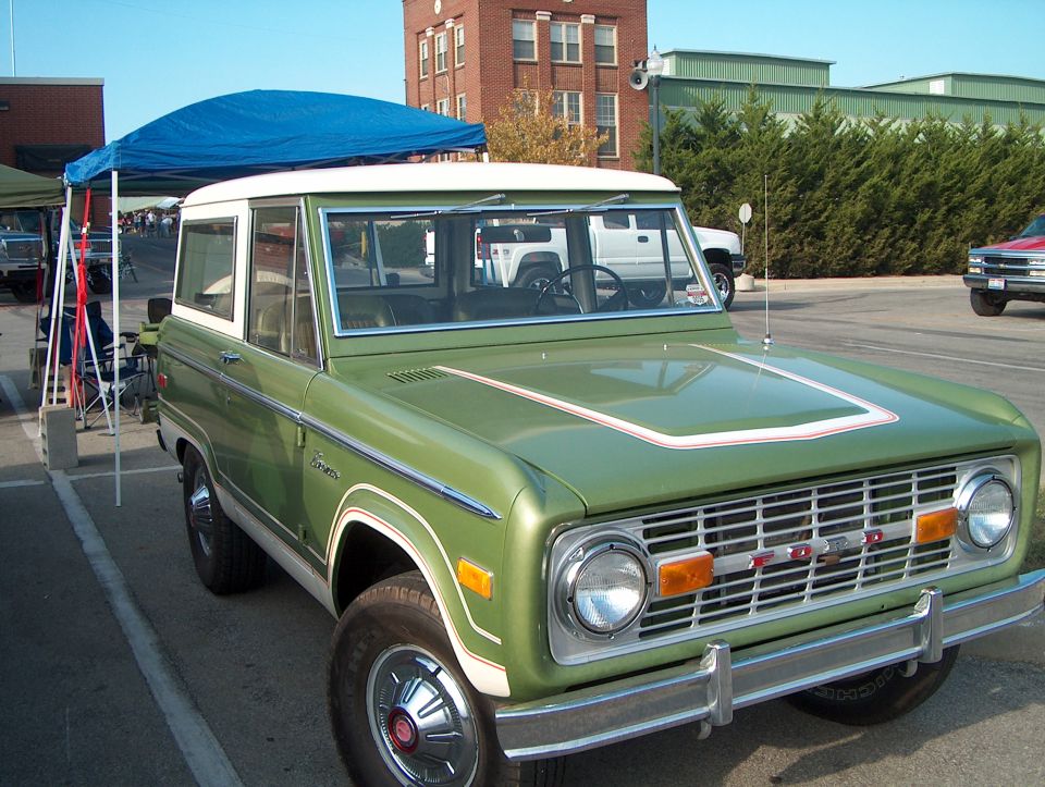 Green 1978 Ford Bronco with white top and hood stripe, front 3/4 view