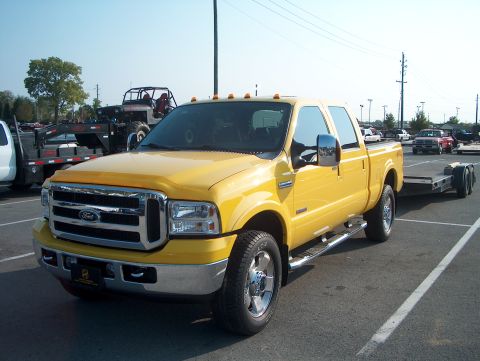 1978 Ford Bronco - A yellow Ford F-250 Super Duty pickup truck is parked in a lot, hitched to a trailer.