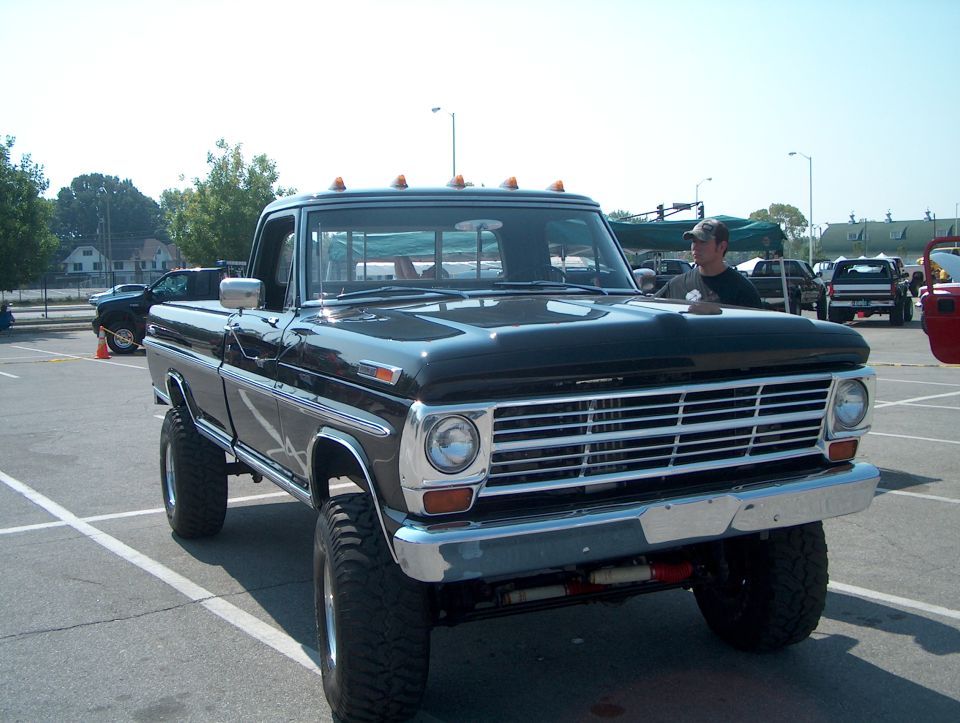 Black lifted pickup truck, 3q-front view. Grille suggests 1970s