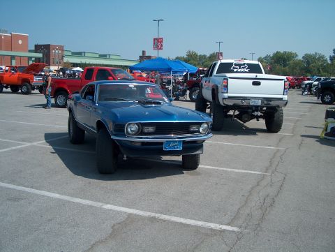 1978 Ford Bronco - A lifted blue 1970 Ford Mustang is parked in a lot with other vehicles.