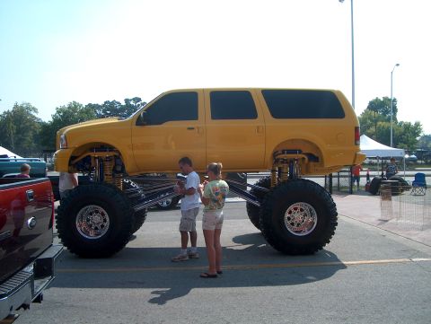 1978 Ford Bronco - A heavily modified yellow SUV with massive tires and suspension is parked outdoors.