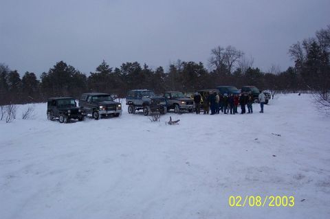1978 Ford Bronco - A group of off-road vehicles are gathered in a snowy landscape under a cloudy sky.
