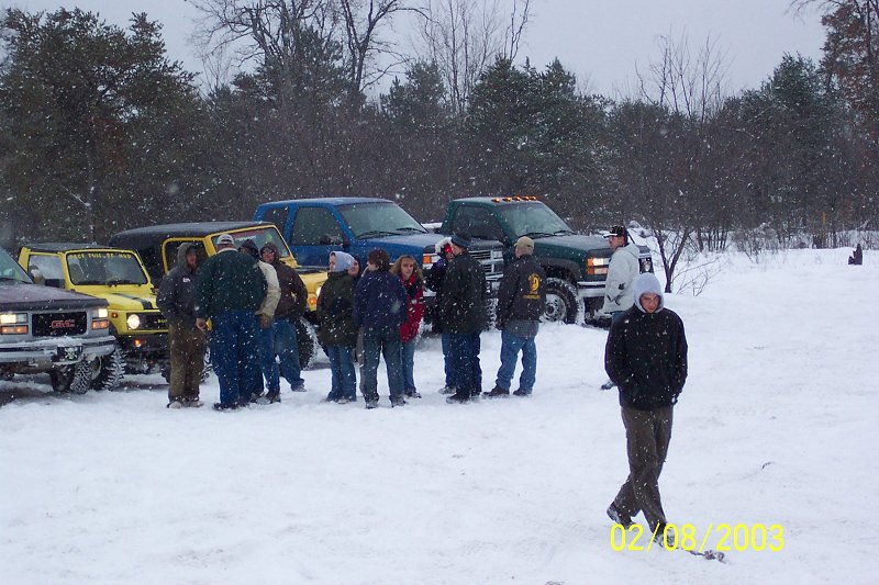 Group of people gathered around several vehicles in a snowy landscape