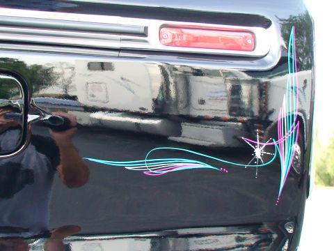 1979 Ford F-250 - A black pickup truck features custom pinstripe artwork on its rear quarter panel, accented by a chrome trim piece and a red taillight.