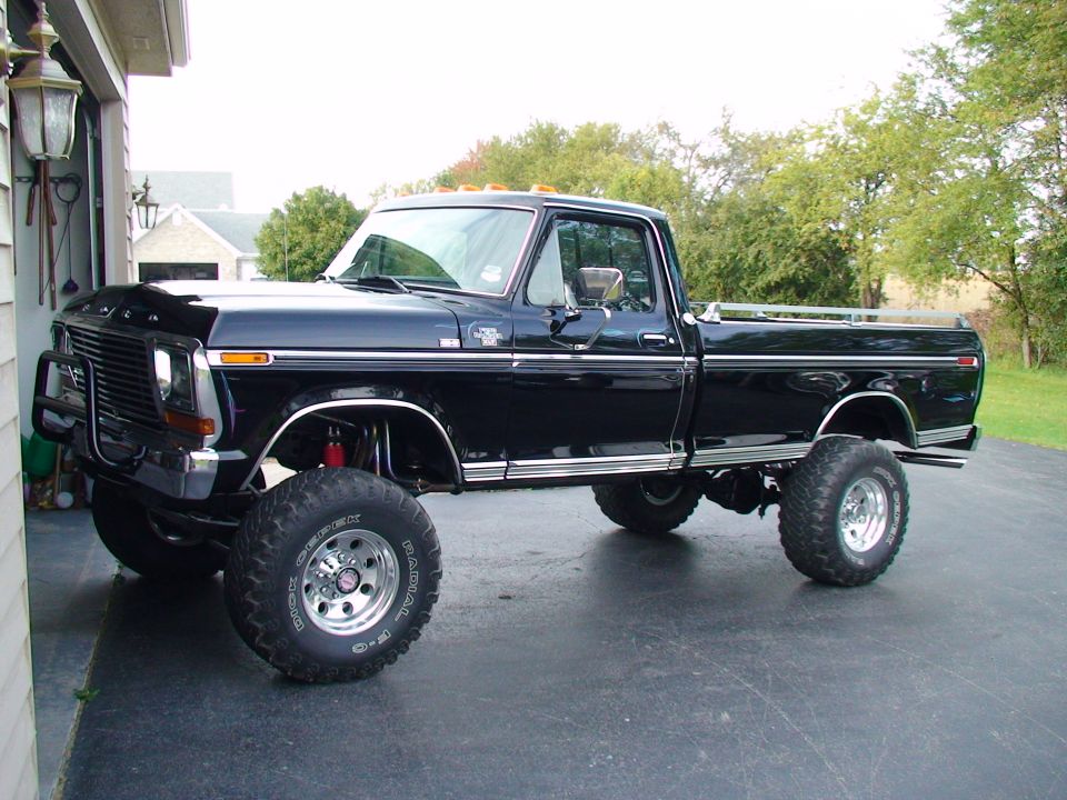 Lifted black Ford F-250 pickup with chrome wheels in a driveway.