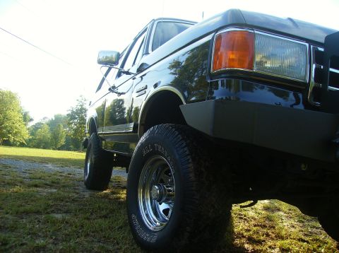 1990 Ford Bronco - This lifted Ford Bronco is shown from a low angle, highlighting its off-road tires and stance.