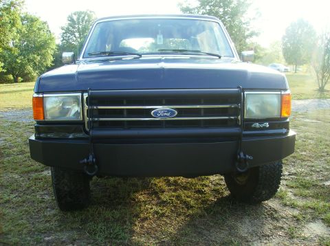 1990 Ford Bronco - Front view of a dark blue Ford Bronco, identifiable by its body style and grille, equipped with a bull bar.