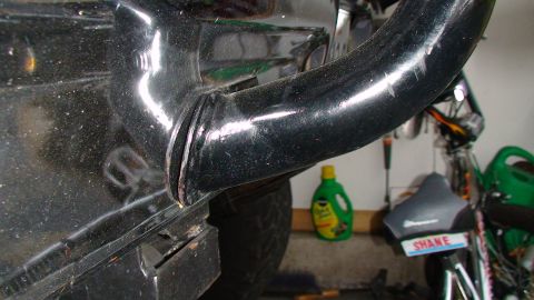 1979 Ford F-250 - Close-up view of a black metal pipe and fender, with various items in the background including a bottle of cleaner and a seat.