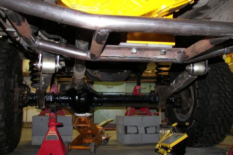 1988 Ford Bronco - Close-up of the undercarriage, focusing on suspension and drivetrain parts, with custom frame work visible.